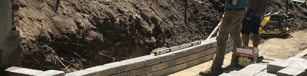 Workers building retaining wall with bricks and tools.